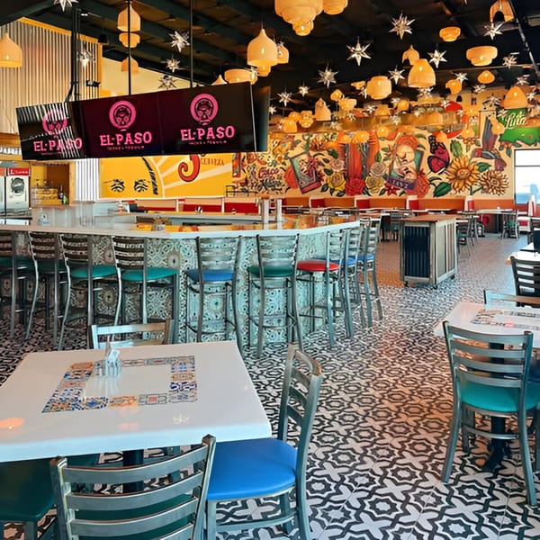 Vibrant El Paso Tacos & Tequila interior with colorful mural, patterned floor, bar seating, and dining tables.