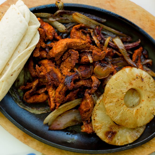 El Paso Tacos & Tequila's sizzling fajitas with chicken, onions, and grilled pineapple, served with tortillas.
