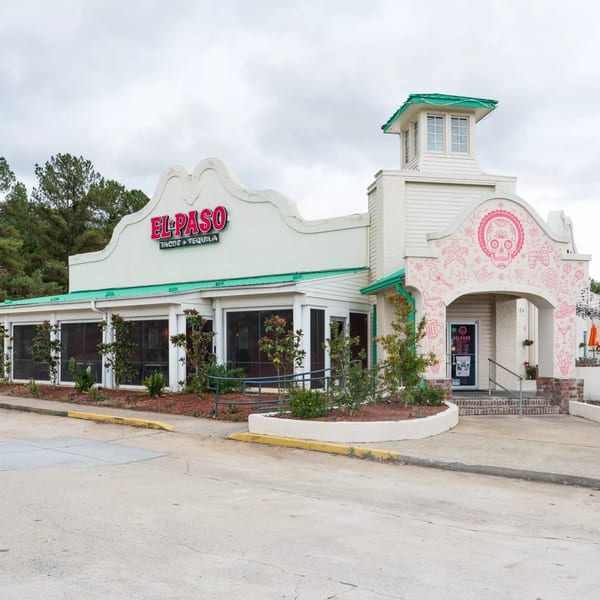 Exterior of El Paso Tacos & Tequila, a white building with a green roof and pink skull mural.