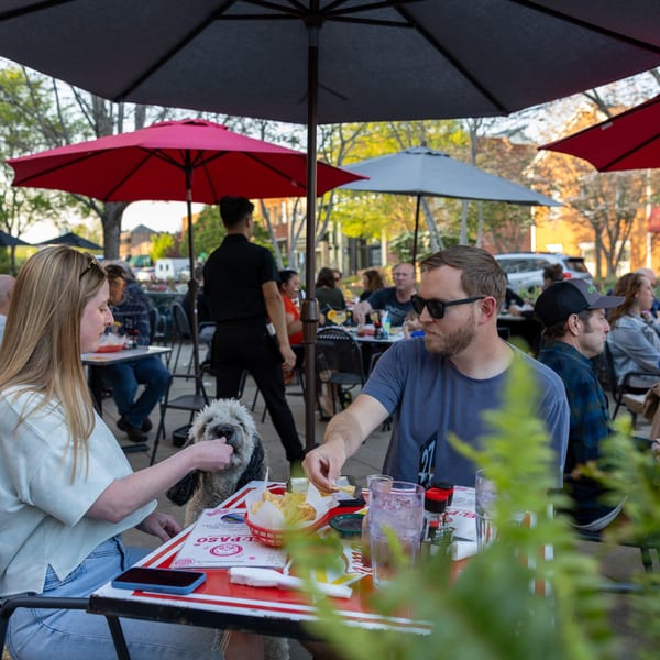 Patrons and a dog enjoy chips and drinks on the outdoor patio of El Paso Tacos & Tequila.