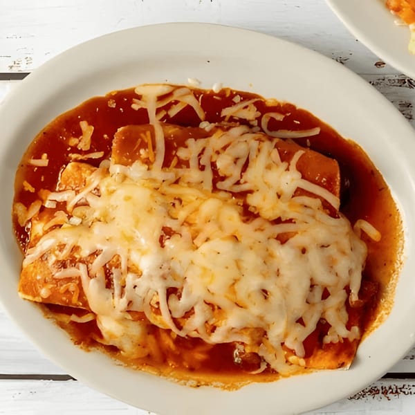 Two cheesy enchiladas covered in red sauce and melted white cheese on a white oval plate.