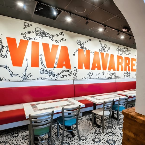 El Paso Tacos & Tequila dining area with red booths, white tables, and a skeleton mural.